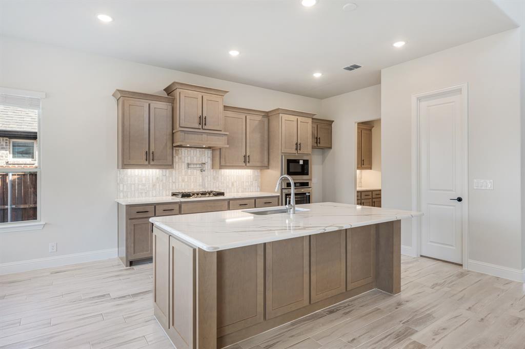 2411 Cornwall Lane Forney, TX 75126 - Photo 14 of 40 a kitchen with a stove a sink and a refrigerator