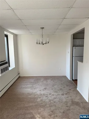 an empty room with chandelier fan and windows