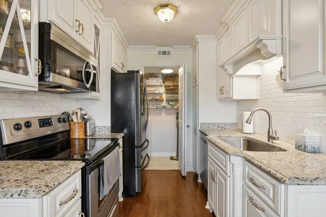 a kitchen with stainless steel appliances granite countertop a sink stove and refrigerator