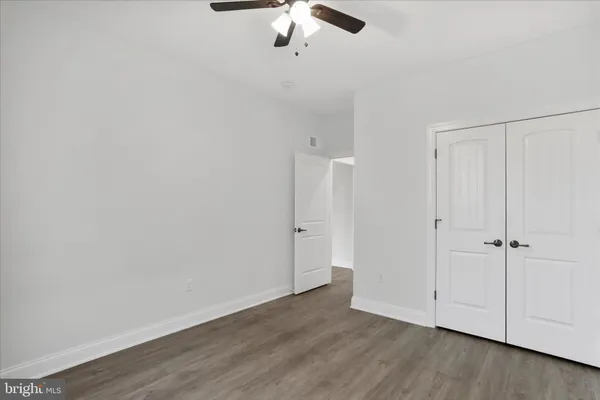 an empty room with wooden floor fan and windows