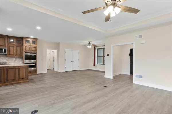 a view of an empty room with a window and kitchen view