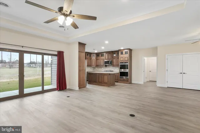 a view of an empty room with a window and kitchen view
