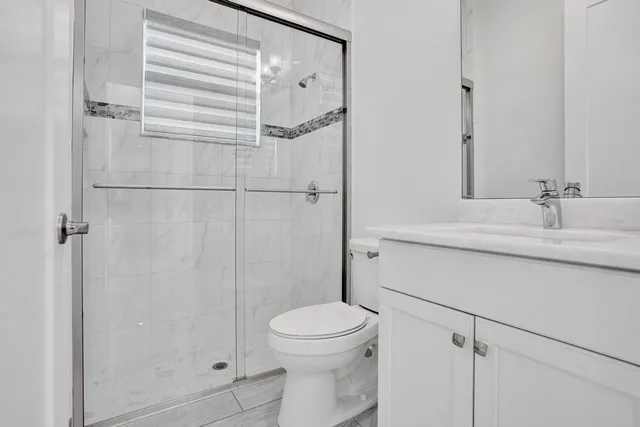 a bathroom with a granite countertop sink a toilet and a shower