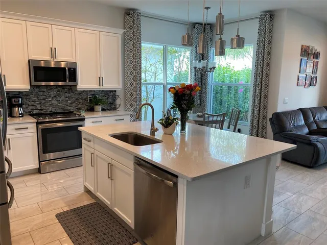 a kitchen with stainless steel appliances granite countertop a sink a microwave a stove and white cabinets