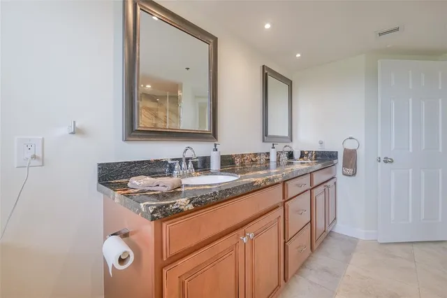 a bathroom with a granite countertop sink toilet mirror and shower
