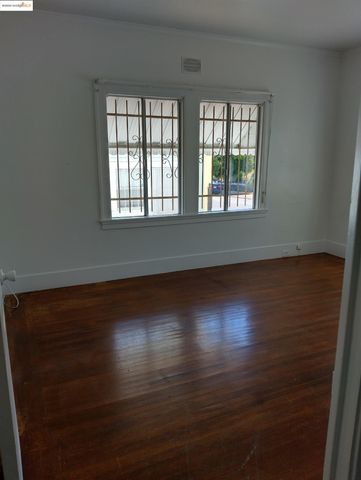 an empty room with wooden floor and windows with curtains
