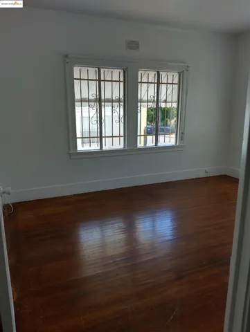 an empty room with wooden floor and windows with curtains