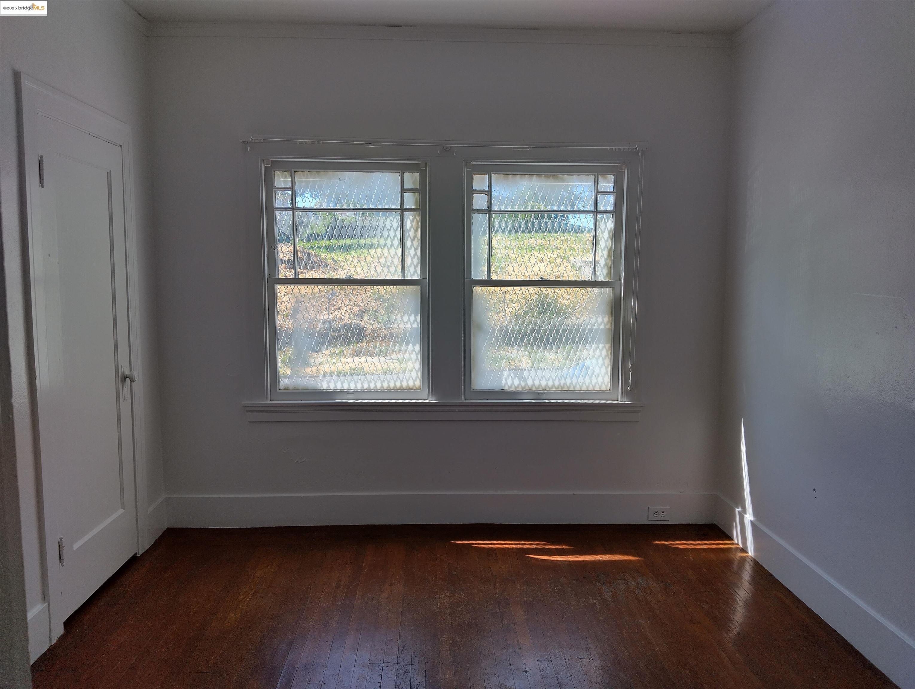 1864 11th Avenue Oakland, CA 94606 - Photo 27 of 46 a view of an empty room with wooden floor and a window