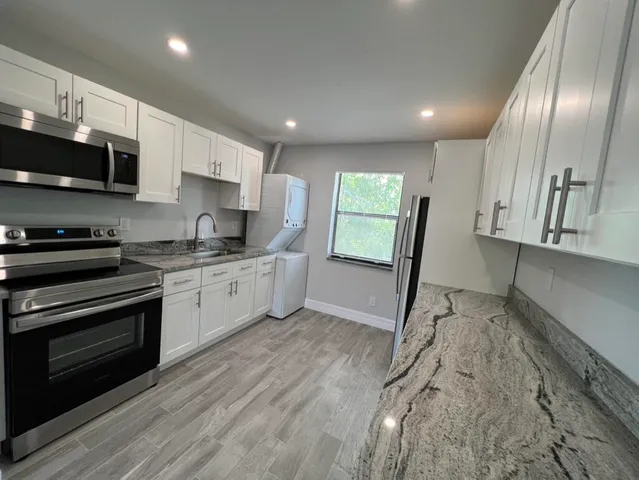 a kitchen with stainless steel appliances granite countertop a stove a sink and a refrigerator