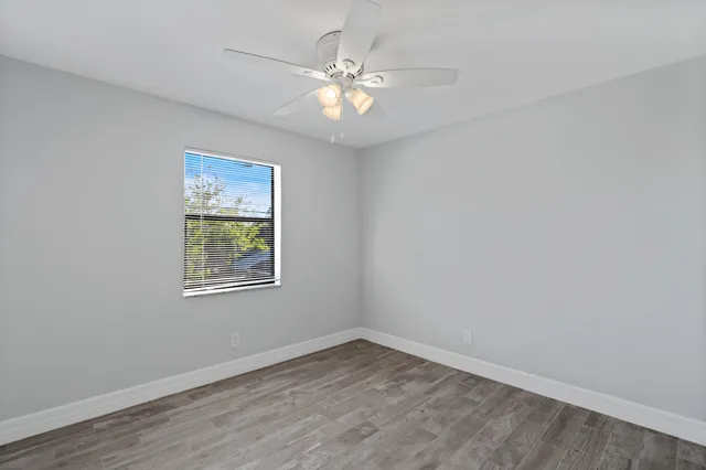 an empty room with a window and a fan