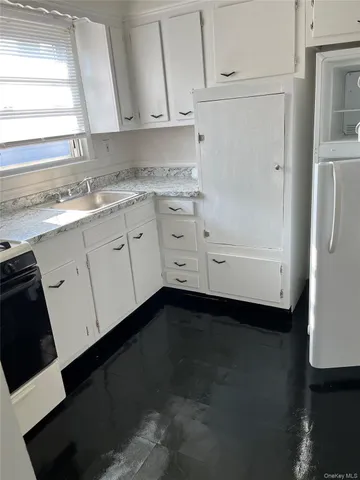 a kitchen with granite countertop white cabinets and a sink