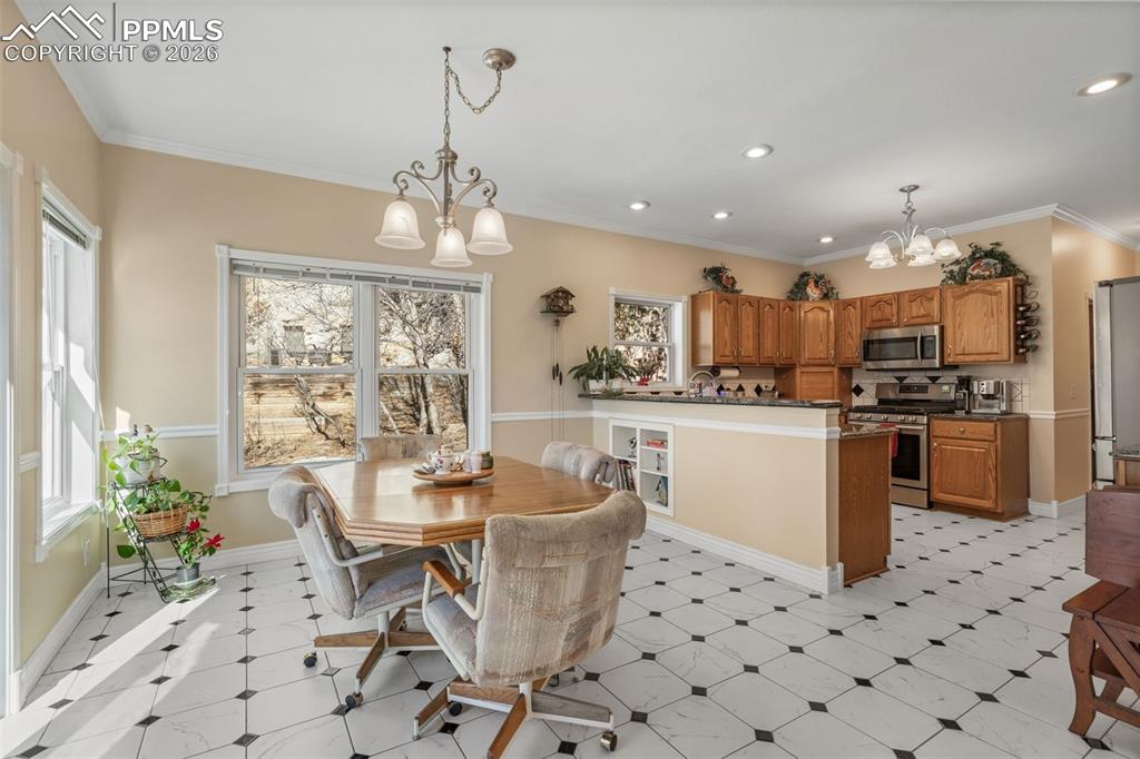 5440 Setters Way Colorado Springs, CO 80919 - Photo 18 of 40 a kitchen with stainless steel appliances kitchen island granite countertop a refrigerator a sink dishwasher a dining table and chairs with wooden floor