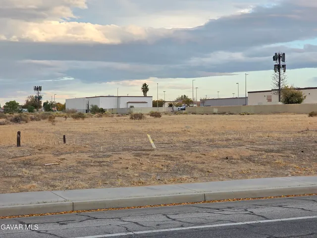 a view of road with card parked on side and retail shops