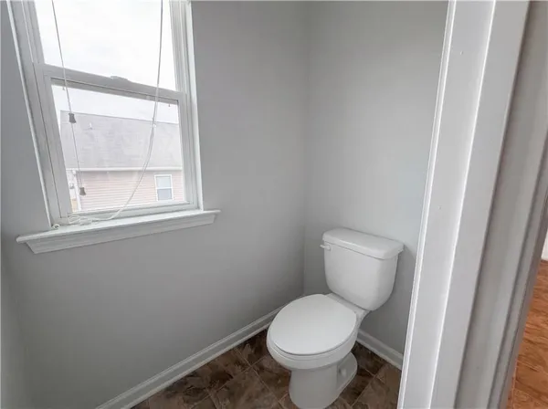 a white toilet sitting in a bathroom next to a window