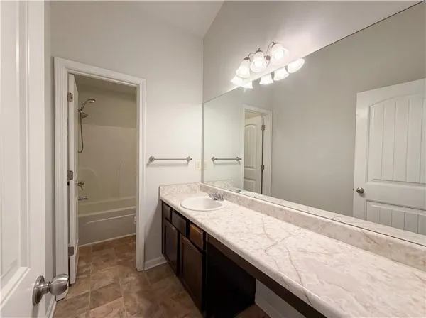 a bathroom with a granite countertop sink a large mirror and a shower