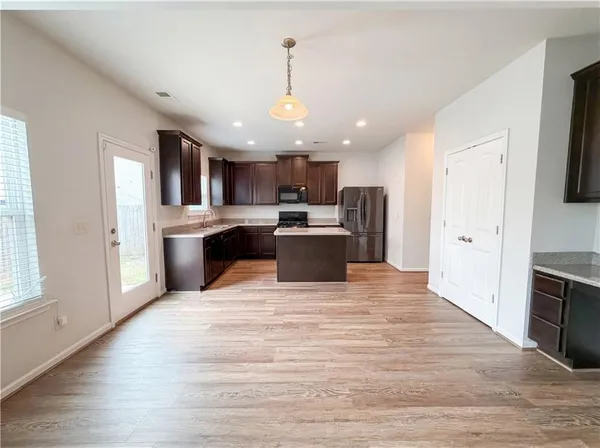 a view of kitchen with kitchen island wooden floor center island and stainless steel appliances