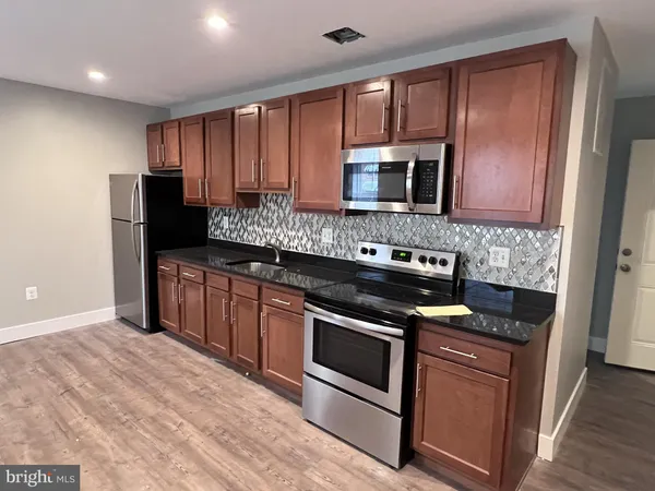 a kitchen with granite countertop wooden cabinets and stainless steel appliances