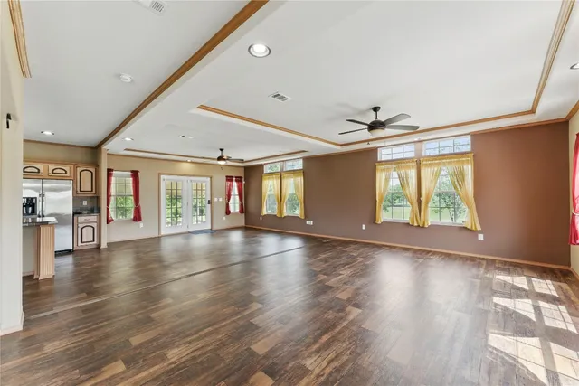 a view of an empty room with kitchen and window