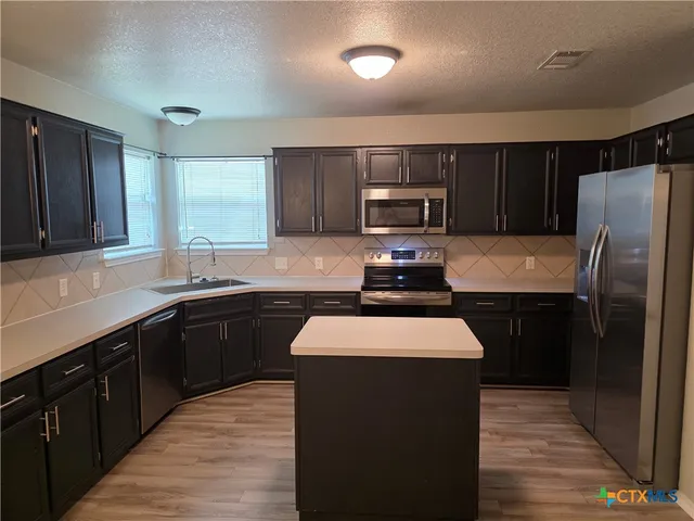 a kitchen with stainless steel appliances wooden cabinets a refrigerator and a sink