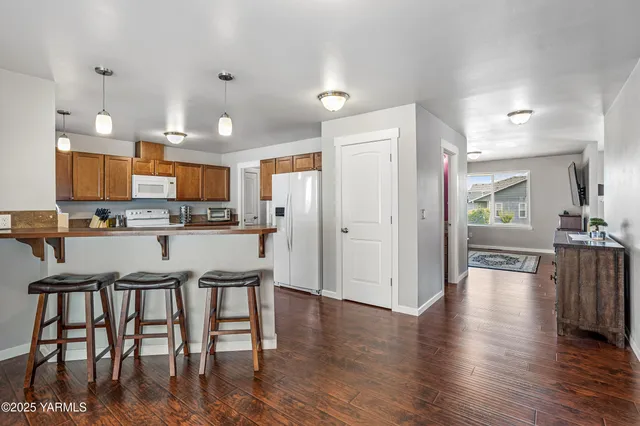 a kitchen with stainless steel appliances kitchen island granite countertop a refrigerator a stove a microwave oven a dining table and chairs with wooden floor