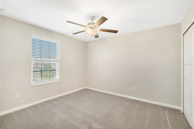 an empty room with a window and a ceiling fan
