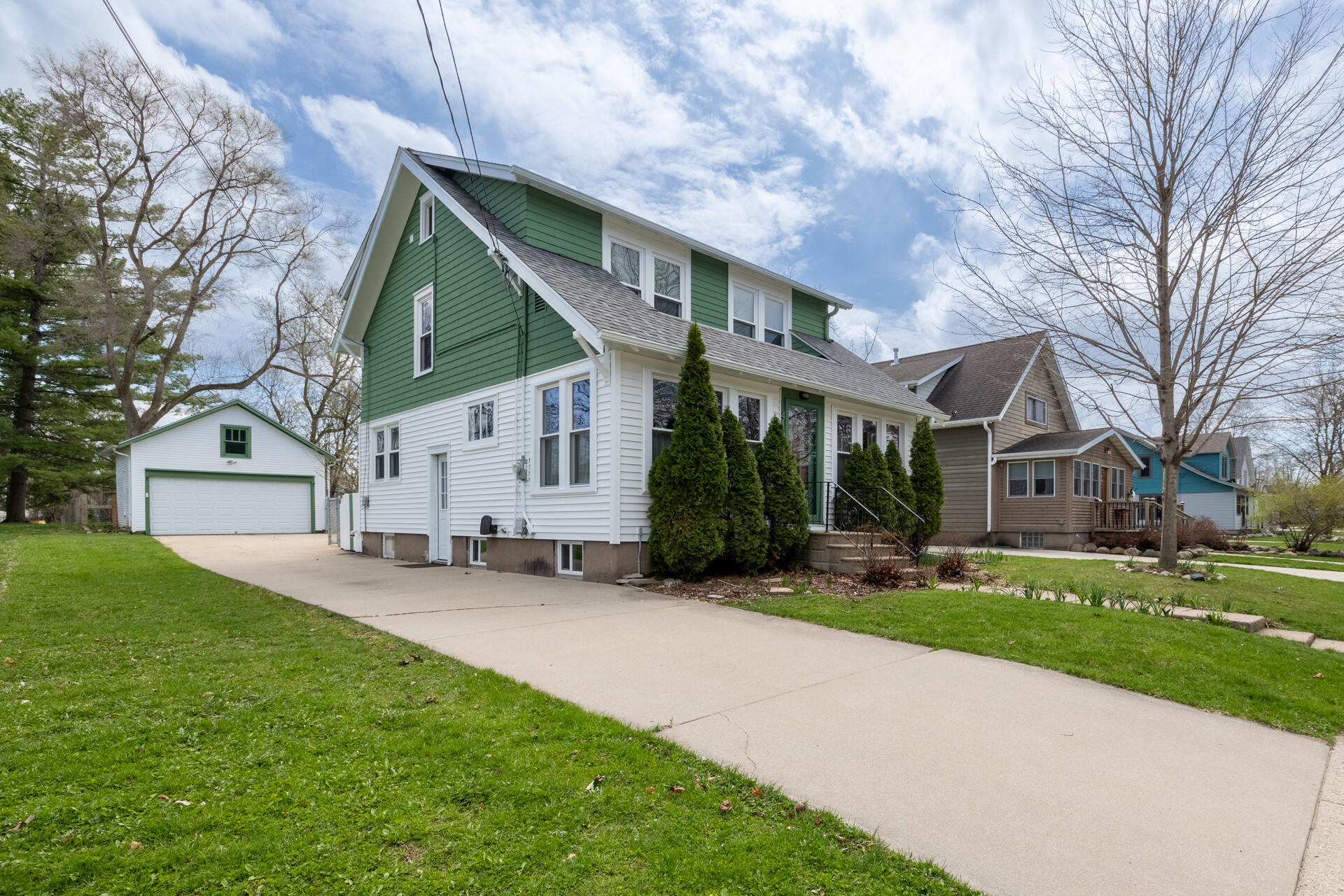 A welcoming exterior with garage and driveway parking, plus a side entry door for easy access to the kitchen and lower level.