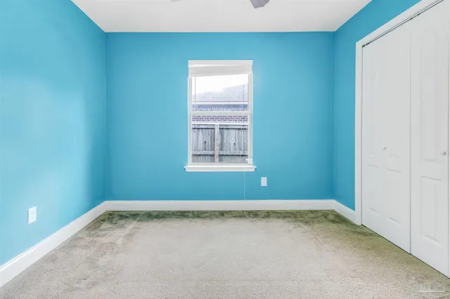 an empty room with a window and a ceiling fan