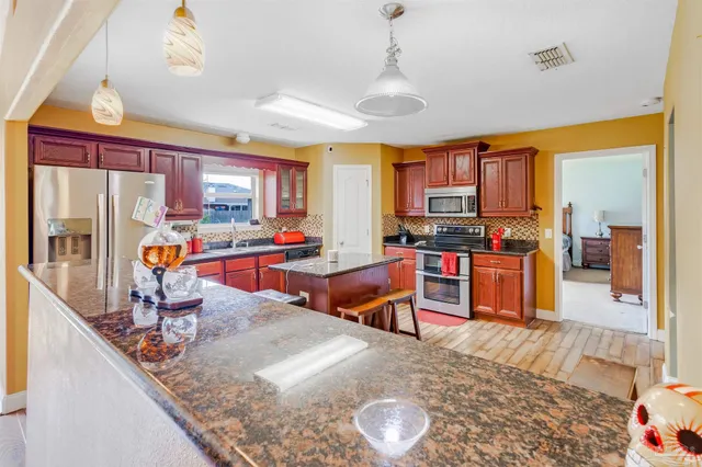 a kitchen with stainless steel appliances granite countertop a stove top oven a sink and cabinets