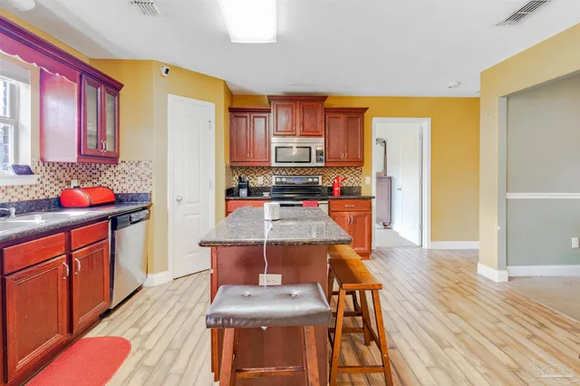 a kitchen with stainless steel appliances a dining table chairs and a refrigerator