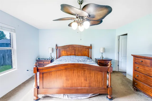 a bedroom with a bed and a large mirror on the dresser