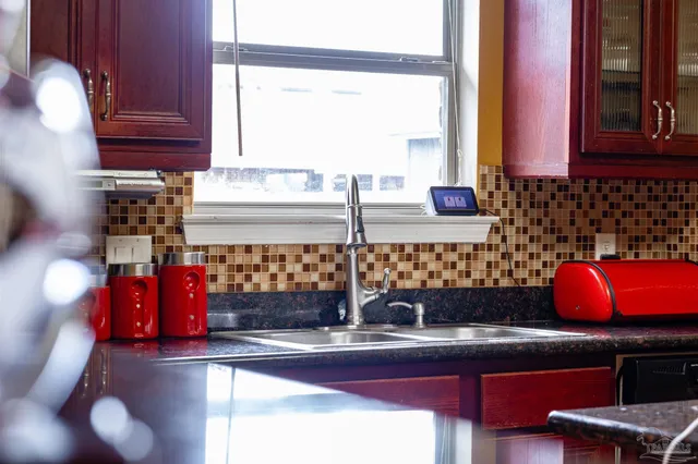 a kitchen with red cabinets window and sink