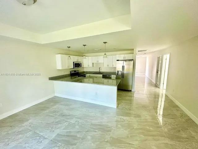 a large kitchen with cabinets and a stainless steel refrigerator