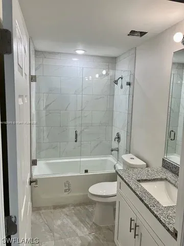 a bathroom with a granite countertop toilet a sink a shower and a mirror