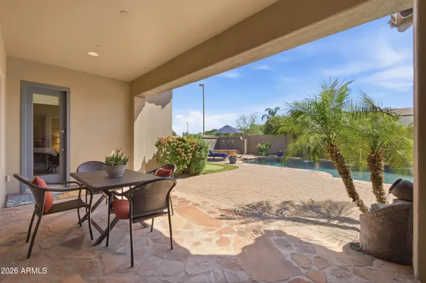 a view of a chairs and table under an umbrella in backyard
