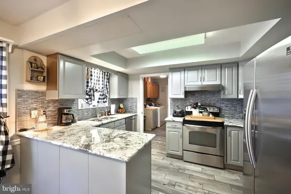 a kitchen with stainless steel appliances granite countertop a sink stove microwave and refrigerator