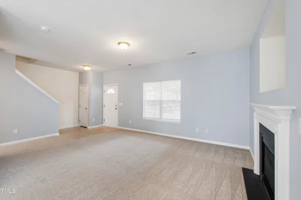 an empty room with windows and fireplace