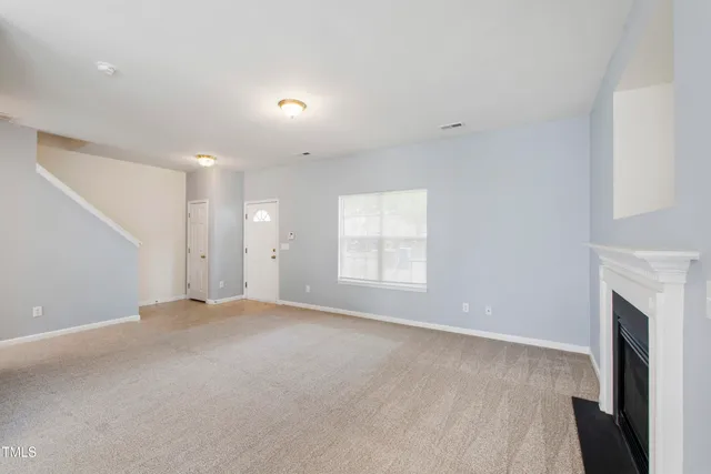 an empty room with windows and fireplace