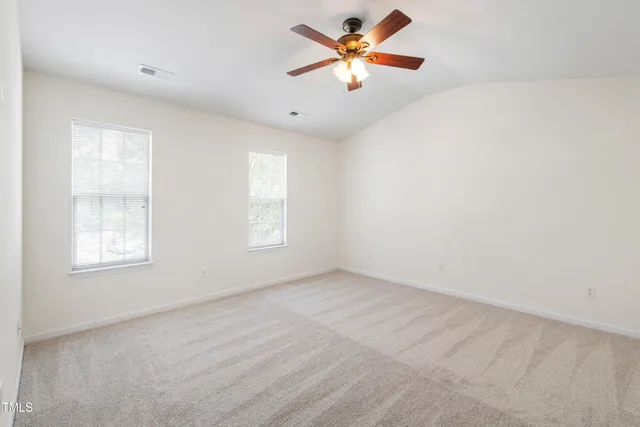 an empty room with windows and fan