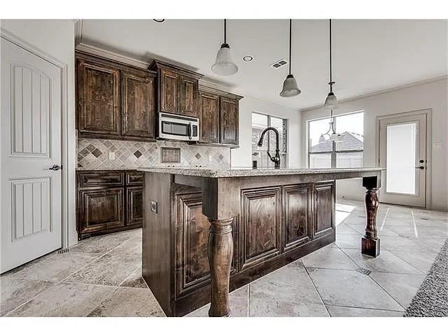 908 Lake Meadow Lane Little Elm, TX 75068 - Photo 6 of 14 a kitchen with stainless steel appliances granite countertop a stove a sink and a microwave