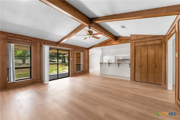 a view of an empty room with a window and wooden floor