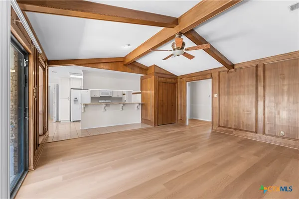 a view of empty room with wooden floor and fan