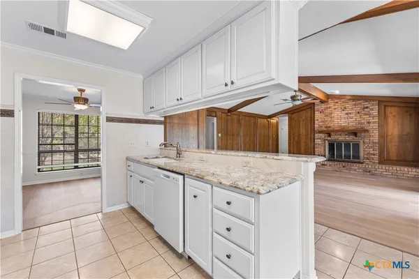 a kitchen with granite countertop a sink window and cabinets