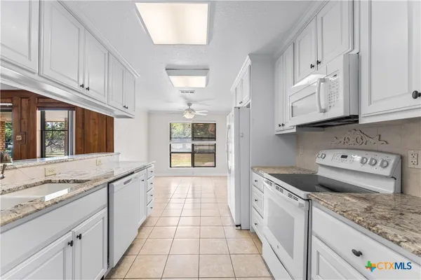 a kitchen with granite countertop a sink stove and cabinets