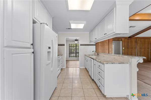 a kitchen with stainless steel appliances kitchen island granite countertop a refrigerator and a sink