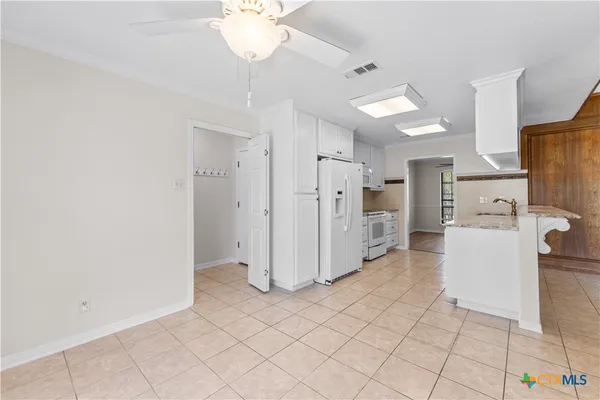 a view of a kitchen with refrigerator and white cabinets