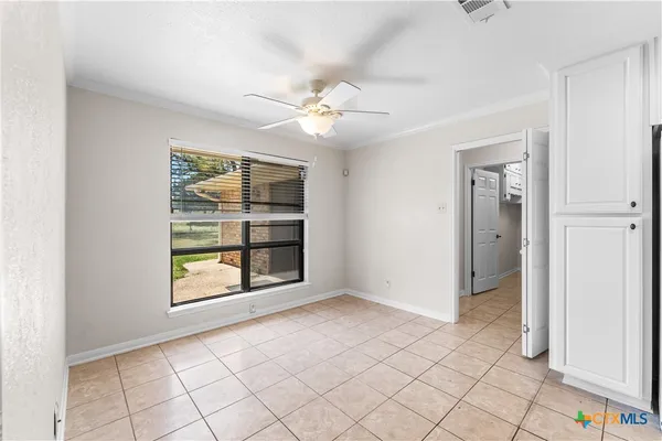 an empty room with chandelier fan and windows
