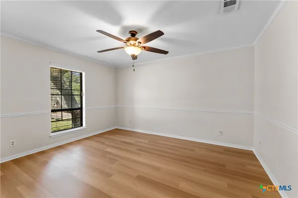an empty room with wooden floor fan and windows