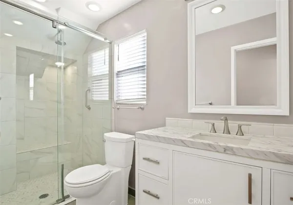 a bathroom with a granite countertop sink toilet a mirror and shower