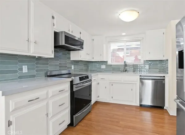 a kitchen with granite countertop white cabinets stainless steel appliances a sink and a window