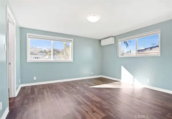 a view of a big room with wooden floor and windows